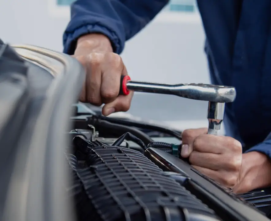 Imagen de un mecánico utilizando una herramienta para reparar un automóvil en referencia a los Talleres y Casas de Repuestos
