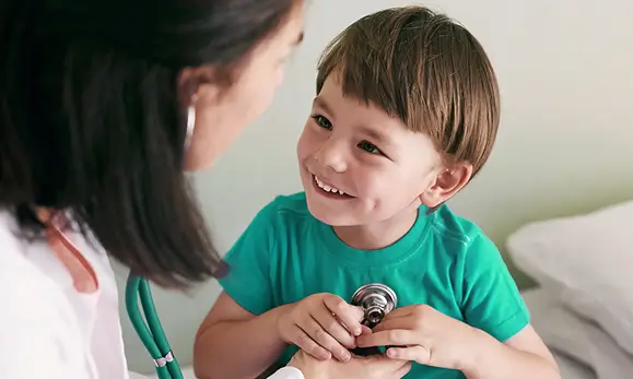 Doctora atendiendo un paciente niño en la Cobertura para menores de edad en referencia a las pólizas de salud de Seguros Caracas y sus beneficios