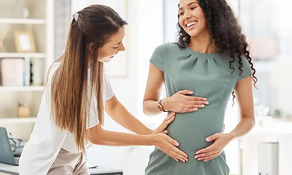 Doctora atendiendo a una paciente embarazada en Maternidad en referencia a las pólizas de salud de Seguros Caracas y sus beneficios